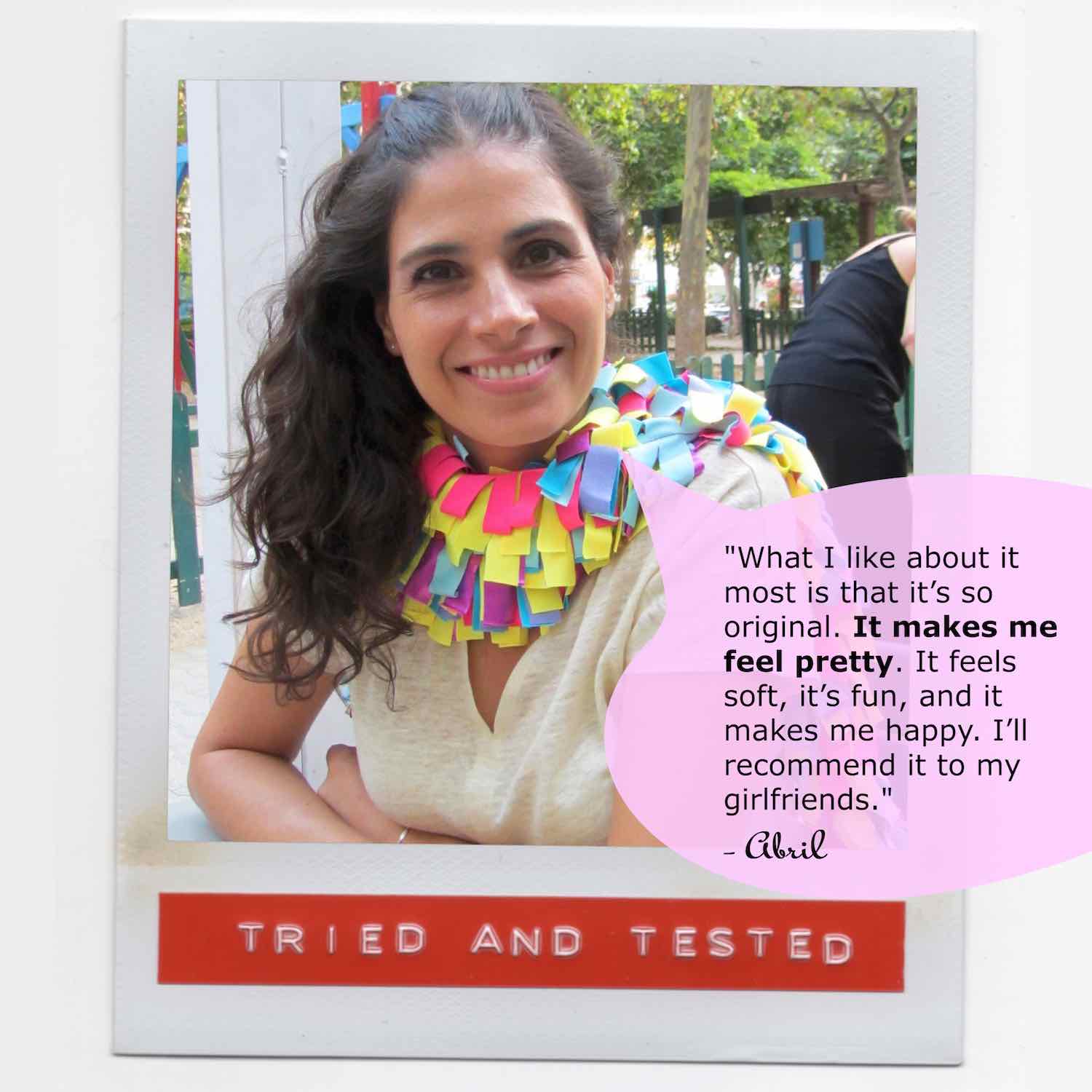 Abril smiling wearing her multicolor fashion boa scarf with style while sitting in an outdoor cafe.