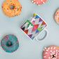 Colorful ceramic coffee mug with quirky slogan Just Ducky in white letters on Flipflop design with happy donuts right view.