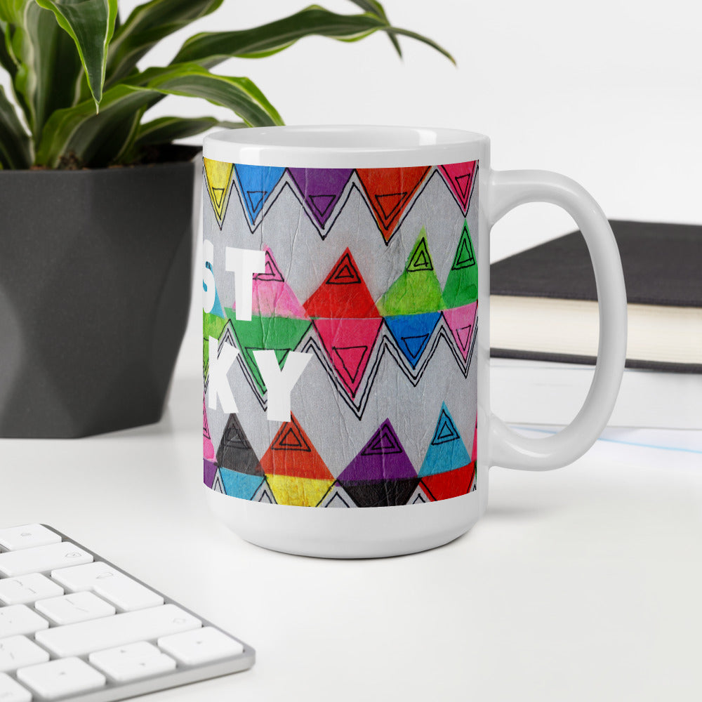 Colorful ceramic coffee mug with quirky slogan Just Ducky in white letters on Flipflop design at white desk right view.