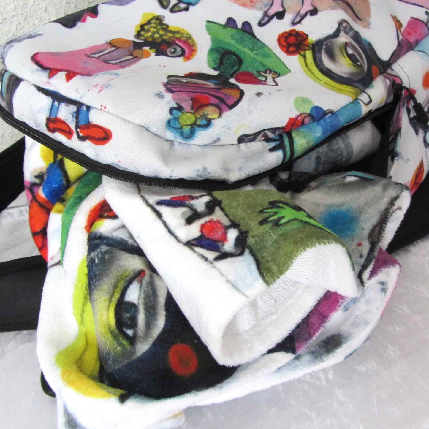 Stylish soft chic beach towel with bold multicolor Fab Ladies print placed inside matching minimal city style backpack.