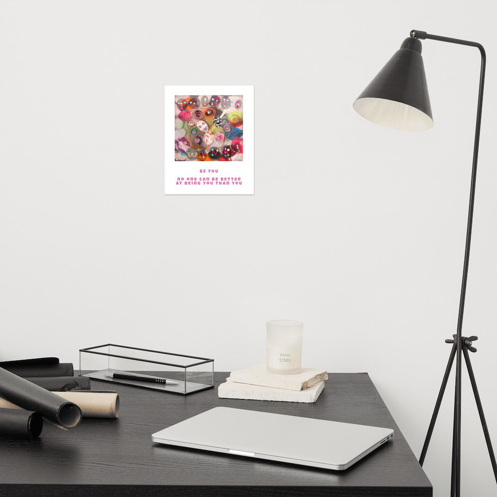 Fine art print Be You hanging on wall at modern desk area. Alex Mitchell’s happy face surrounded by colorful shapes and textures.