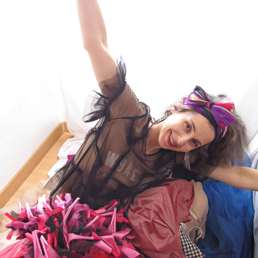 Alex Mitchell smiling and feeling happy with arms outstretched underneath a pile of clothes from her closet.