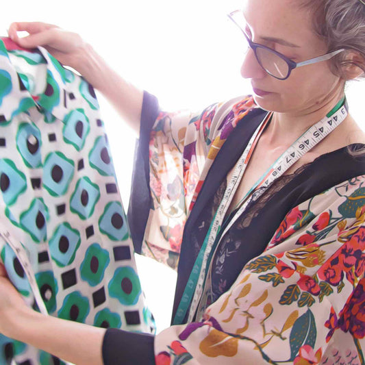 Alex Mitchell checking the materials and colors of a stylish blouse with green and blue graphic pattern.