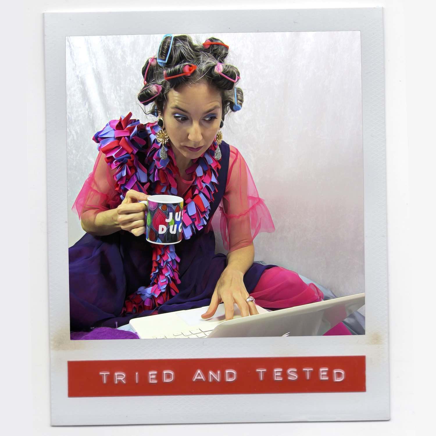 Alex Mitchell all dressed up drinking coffee with curlers in her hair feeling fab and wearing a colorful stylish lush boa scarf.