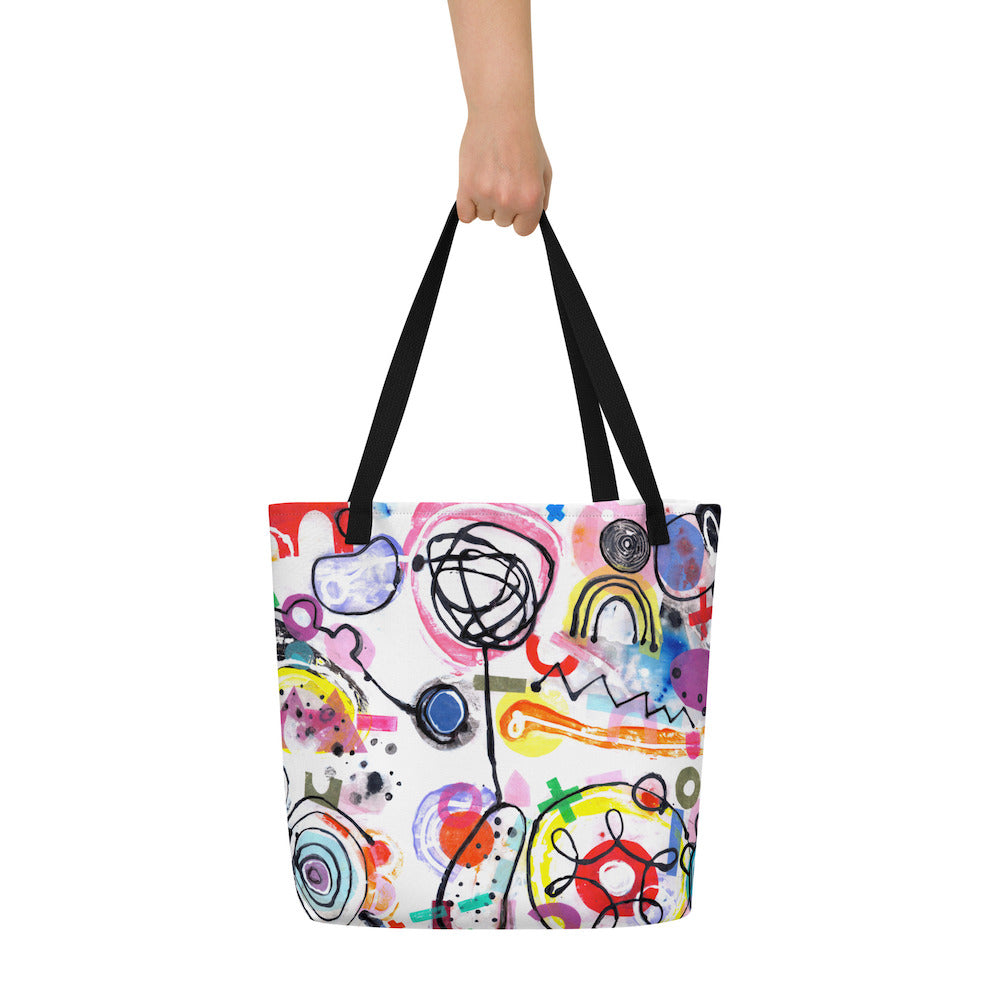 Big sturdy graphic tote bag with multicolor Bazinga s print on front and black straps held up with hand.