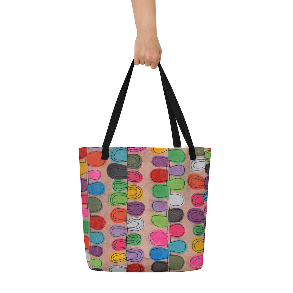 Big sturdy graphic tote bag with multicolor Flipflop print on front and black straps held by hand.
