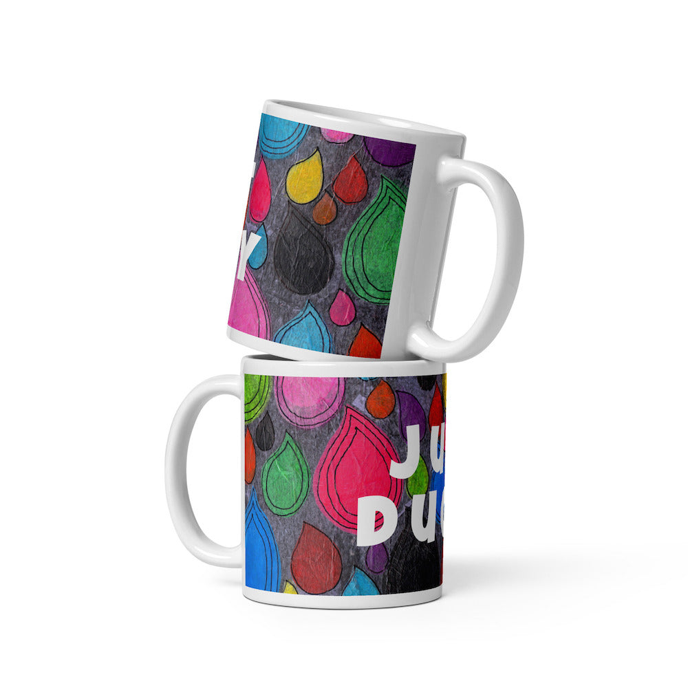Two stacked colorful ceramic 11 ounce coffee mugs with quirky slogan Just Ducky in white letters on Dripdrop design.