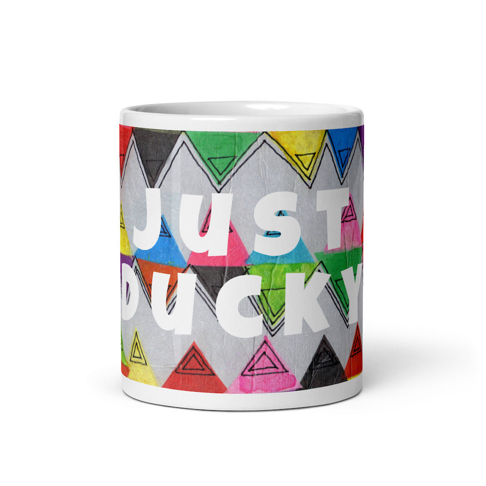 Colorful ceramic coffee mug with quirky slogan Just Ducky in white letters on Zigzag design, front view of 11 ounce mug size.