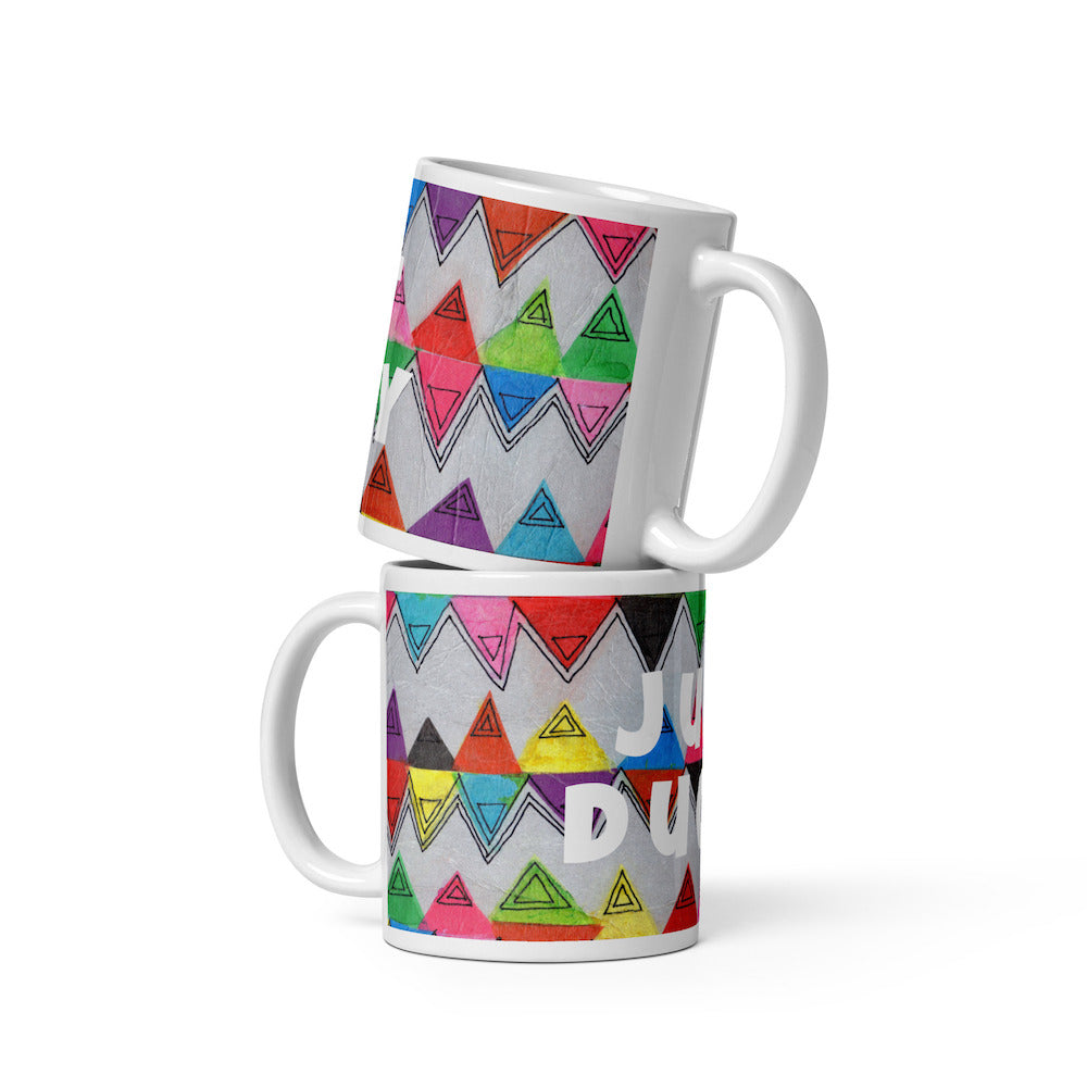 Two stacked colorful ceramic 11 ounce coffee mugs with quirky slogan Just Ducky in white letters on Zigzag design.