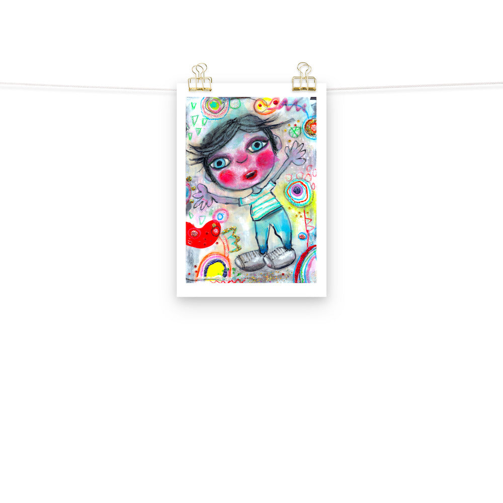 Colorful happy fine art print of a little boy surprised and excited on vibrant background hanging on wall from a string with gold clips.