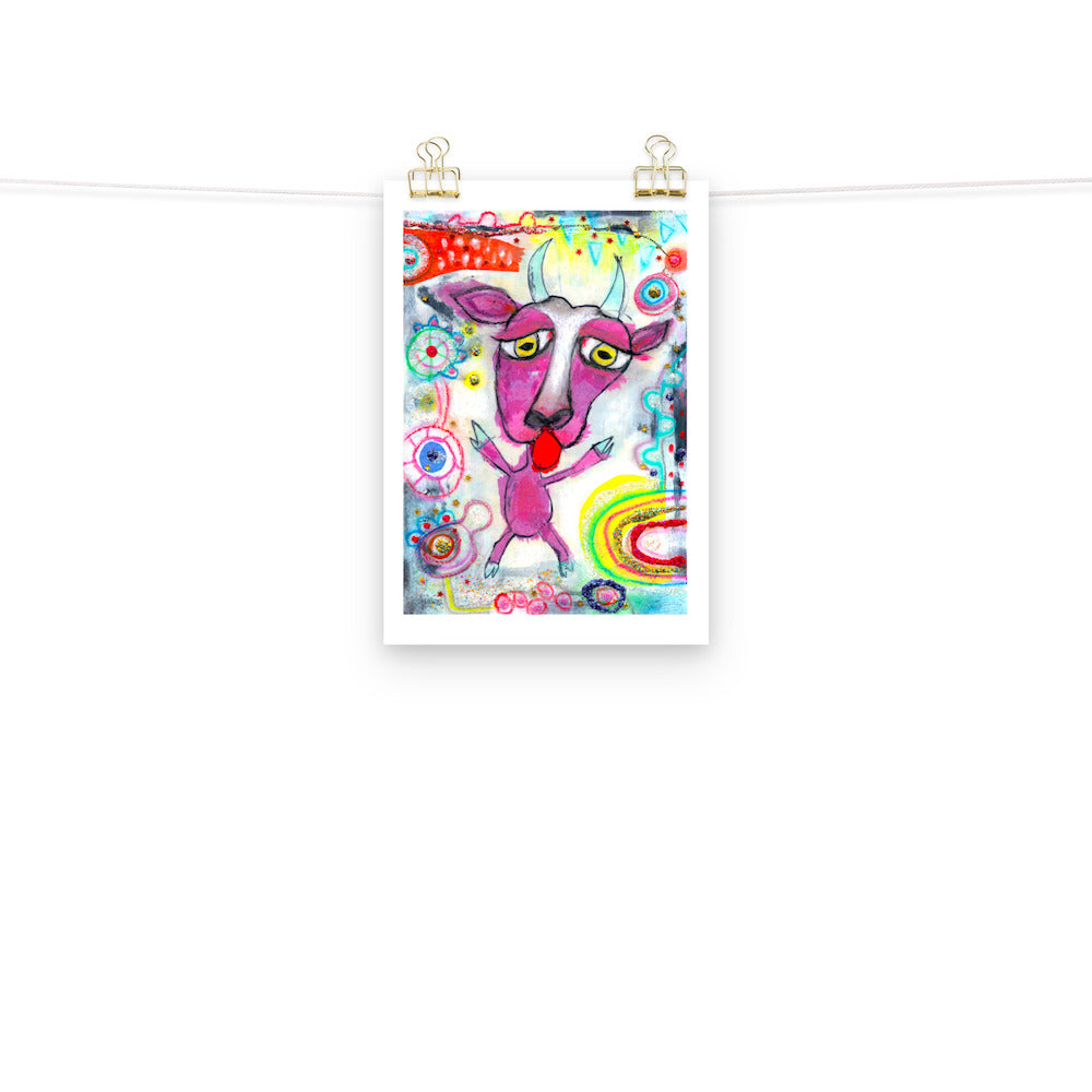 Colorful happy fine art print of a purple goat sticking out tongue on vibrant background hanging on wall from a string with gold clips.
