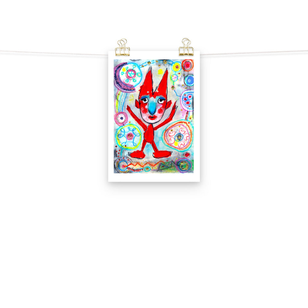 Colorful happy fine art print of a red devil pointing on vibrant background hanging on wall from a string with gold clips.