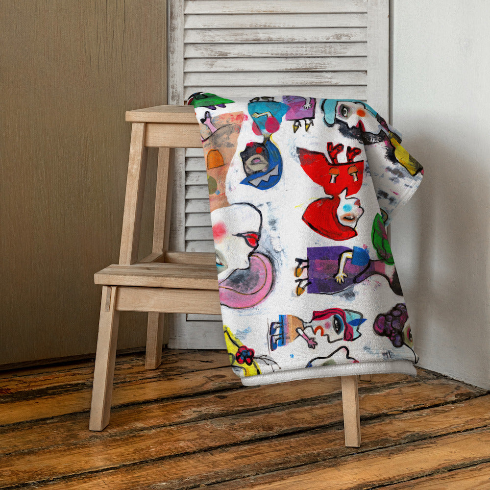 Stylish soft chic beach towel with bold multicolor Fab Ladies print in cheerful and playful style. Folded and hanging on stool.