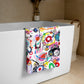 Stylish soft chic beach towel with bold multicolor Treasure Map print in cheerful and playful style. Folded and hanging over bathtub.
