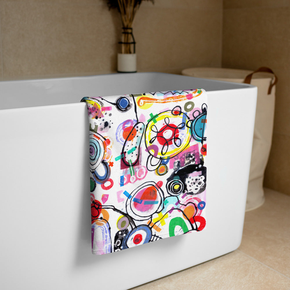 Stylish soft chic beach towel with bold multicolor Treasure Map print in cheerful and playful style. Folded and hanging over bathtub.