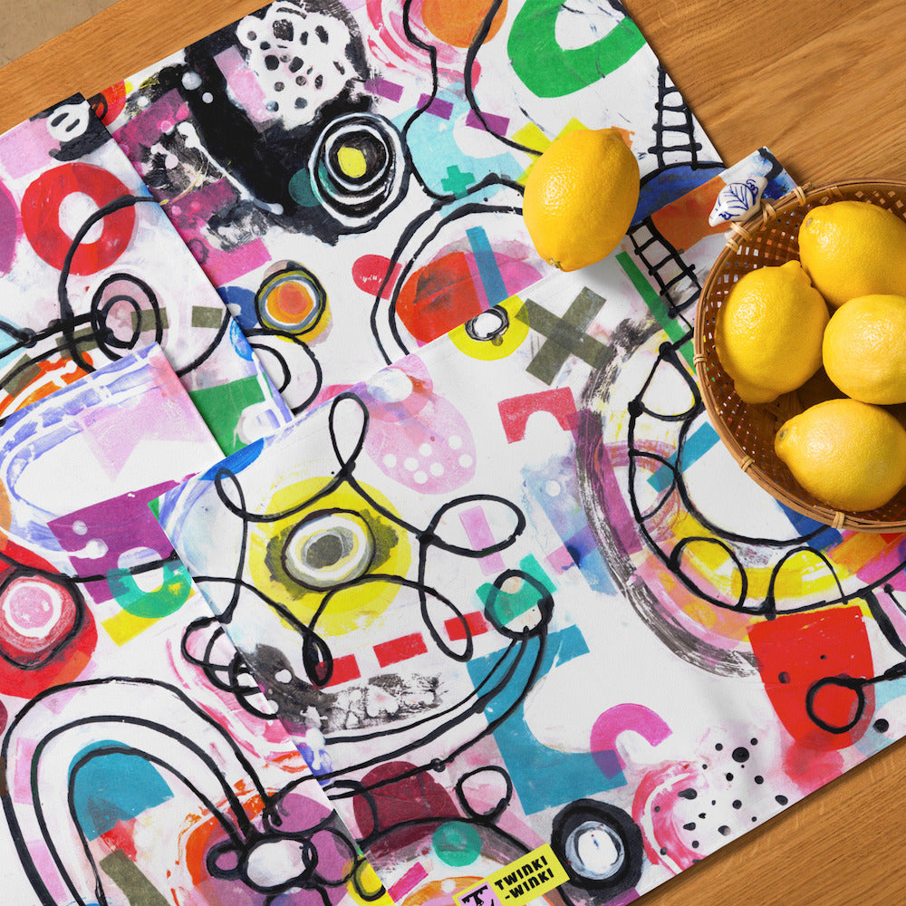 Arty graphic placemat set on wood table with happy multicolor Treasure Map print in a vibrant, cheerful, and playful style, with lemons in bowl.