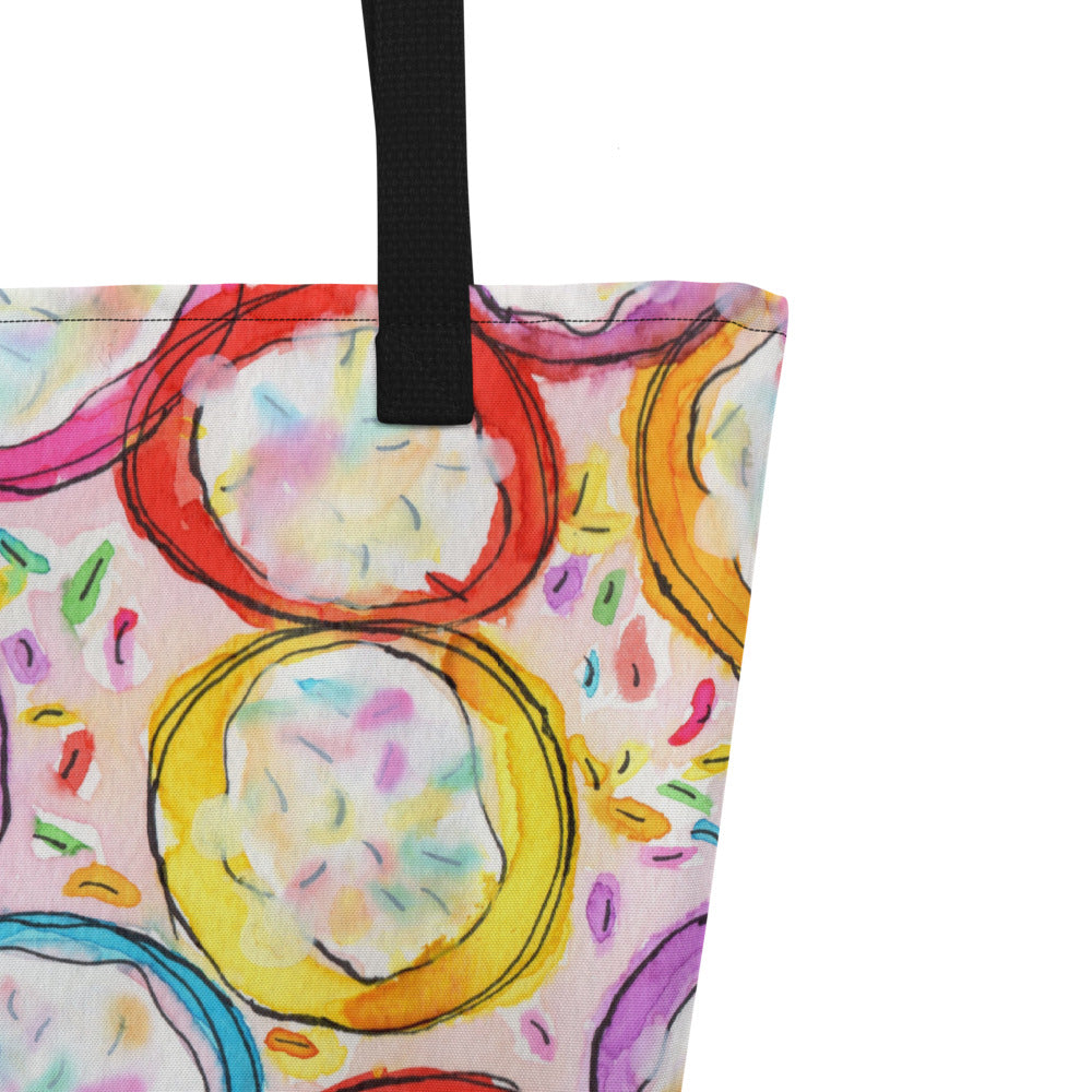 Close-up of black shoulder strap on multicolor Frosted Cookies print on front of graphic tote bag.
