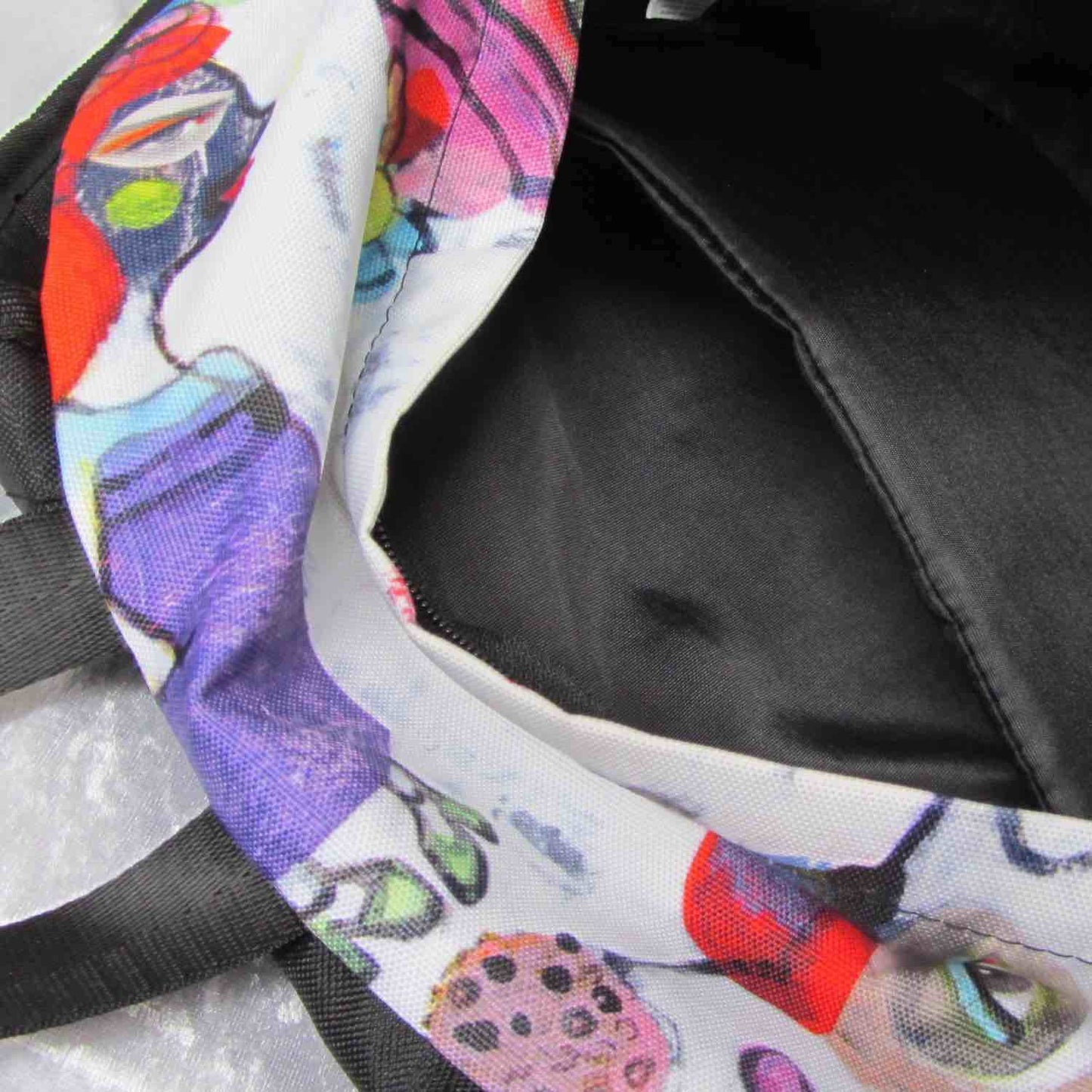 Detail of graphic minimal design city style backpack with fun multicolor Fab Ladies print and black interior padded pocket.