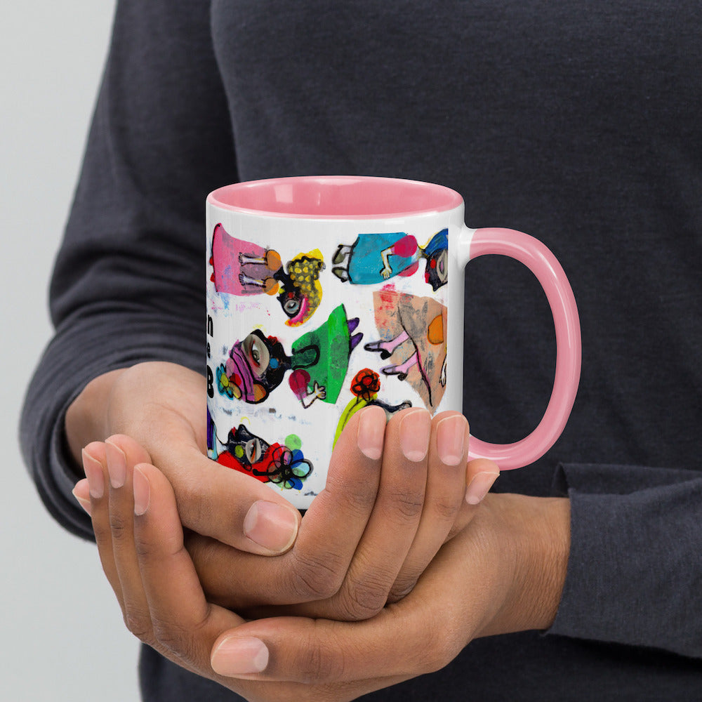 Graphic coffee mug with slogan Born To Be Fab and pink accent color on rim and handle, hands holding right view.