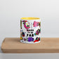 Graphic coffee mug with slogan Born To Be Fab and yellow accent color on rim and interior on wood counter front view.