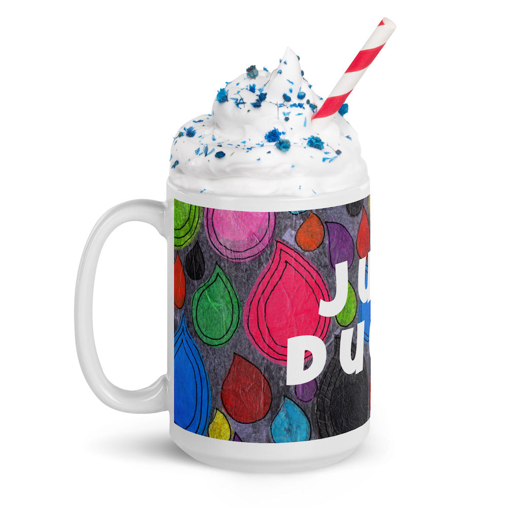 Colorful ceramic coffee mug with quirky slogan Just Ducky in white letters on Dripdrop design with whipped cream left view.