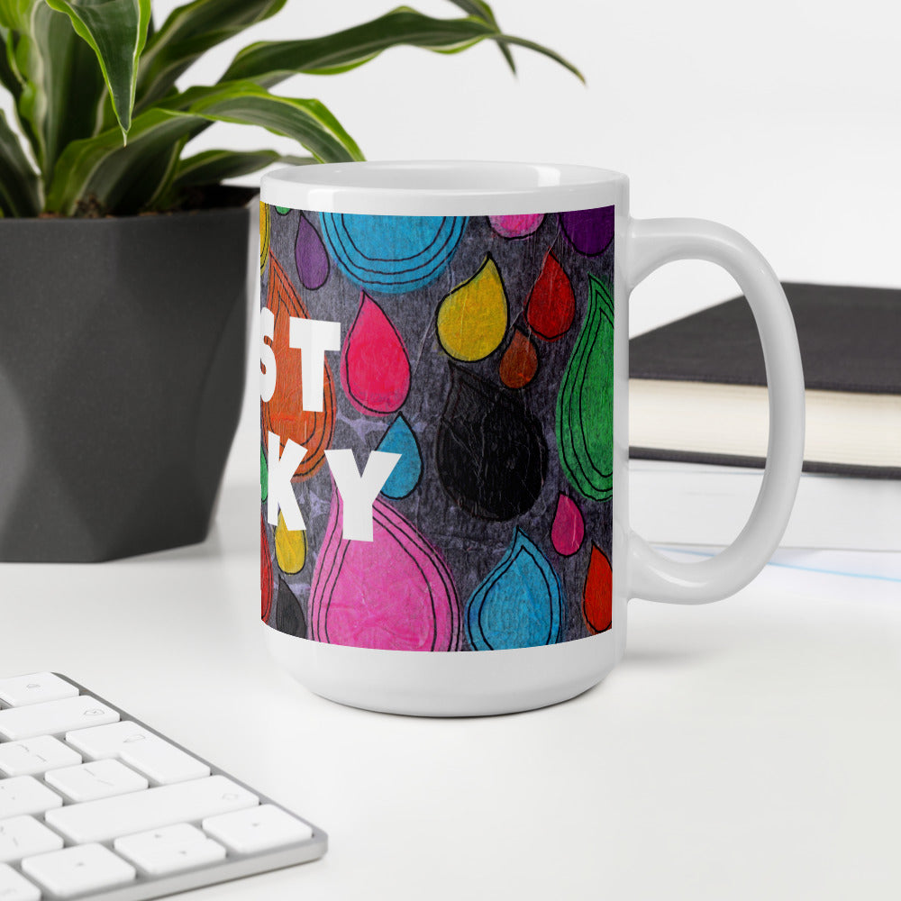 Colorful ceramic coffee mug with quirky slogan Just Ducky in white letters on Dripdrop design at white desk right view.
