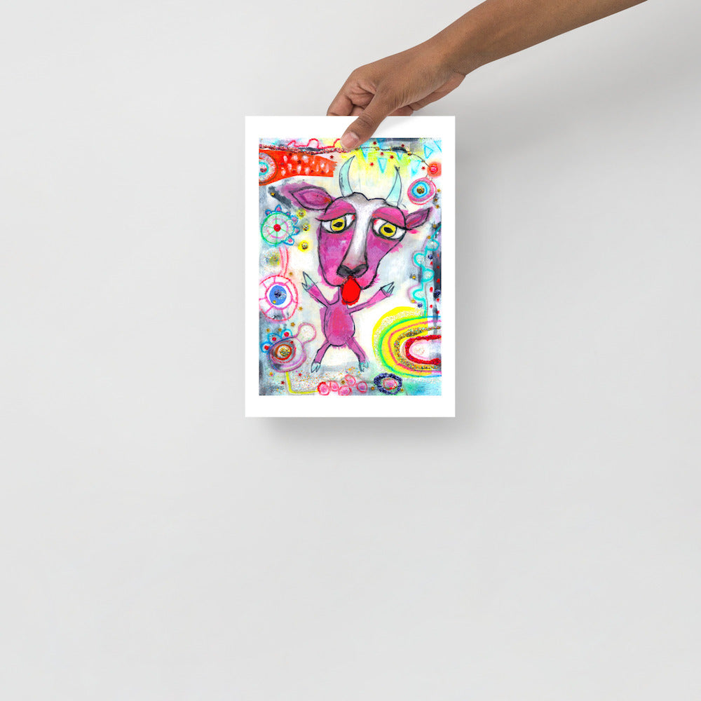 Colorful happy fine art print of a purple goat sticking out tongue on vibrant background hand held against wall to show size.