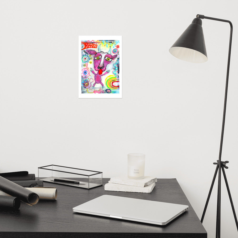 Colorful happy fine art print of a purple goat sticking out tongue on vibrant background hanging on wall at modern desk area.