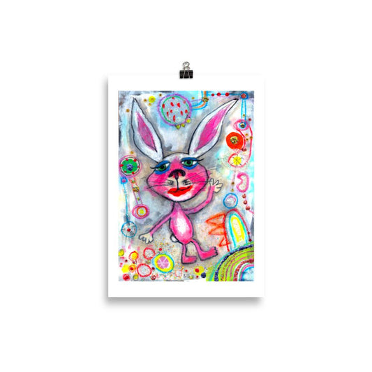 Colorful happy fine art print of a pink rabbit waving hello on vibrant background hanging on wall from a binder clip.