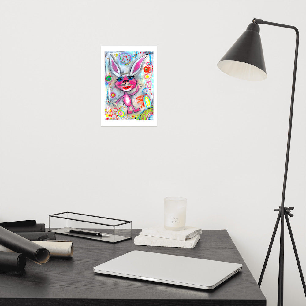 Detail of colorful happy fine art print of a pink rabbit waving hello on vibrant background hanging on wall at modern desk area.