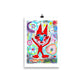 Colorful happy fine art print of a red devil pointing on vibrant background hanging on wall from a binder clip.