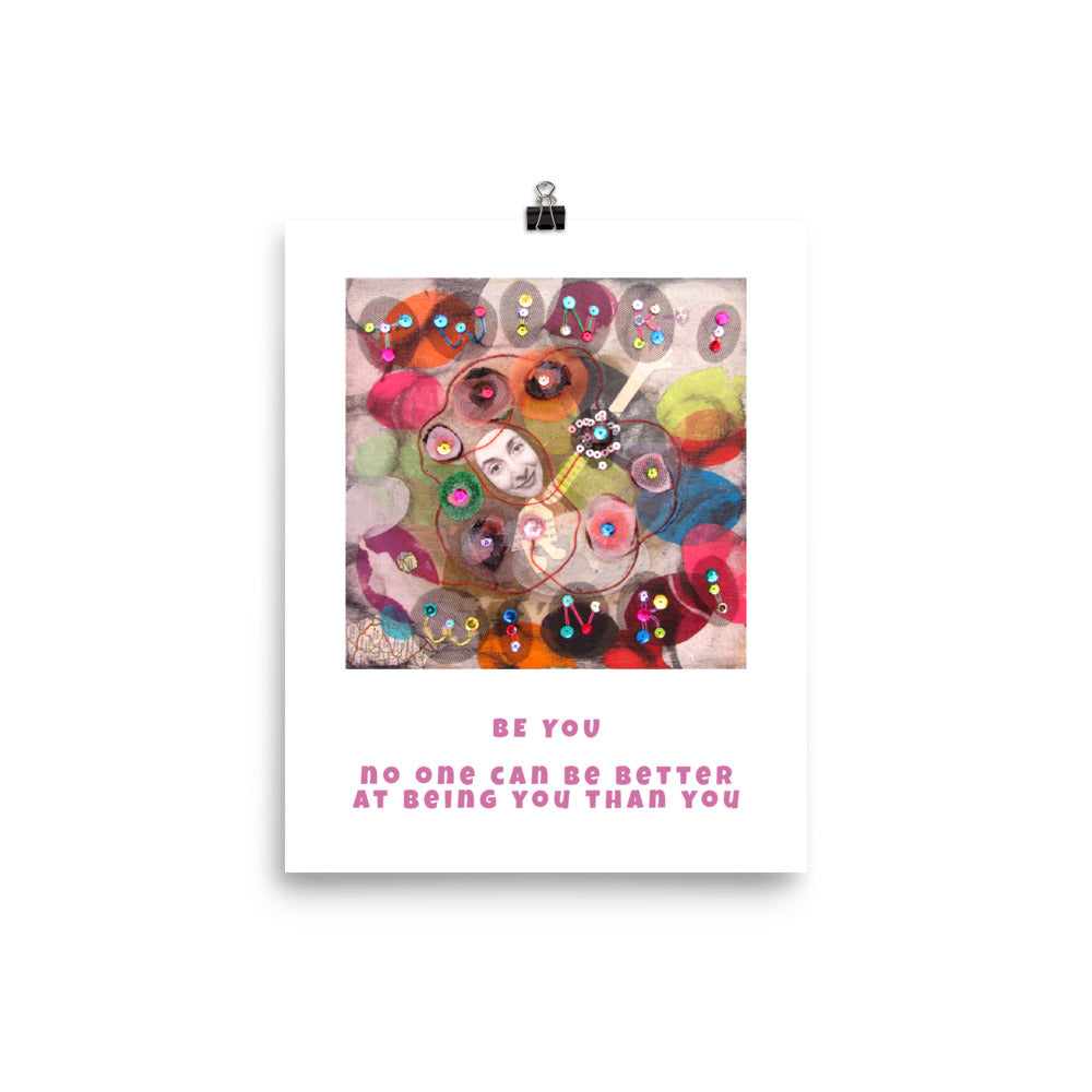 Fine art print Be You hanging with a binder clip. Alex Mitchell’s happy face surrounded by colorful shapes and textures.