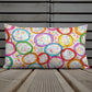 Vibrant, cheerful, and playful style accent pillow on wood deck with a multicolor graphic Frosted Cookies print on front.