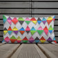 Vibrant, cheerful, and playful style accent pillow on wood deck with a multicolor graphic Zigzag print on front.