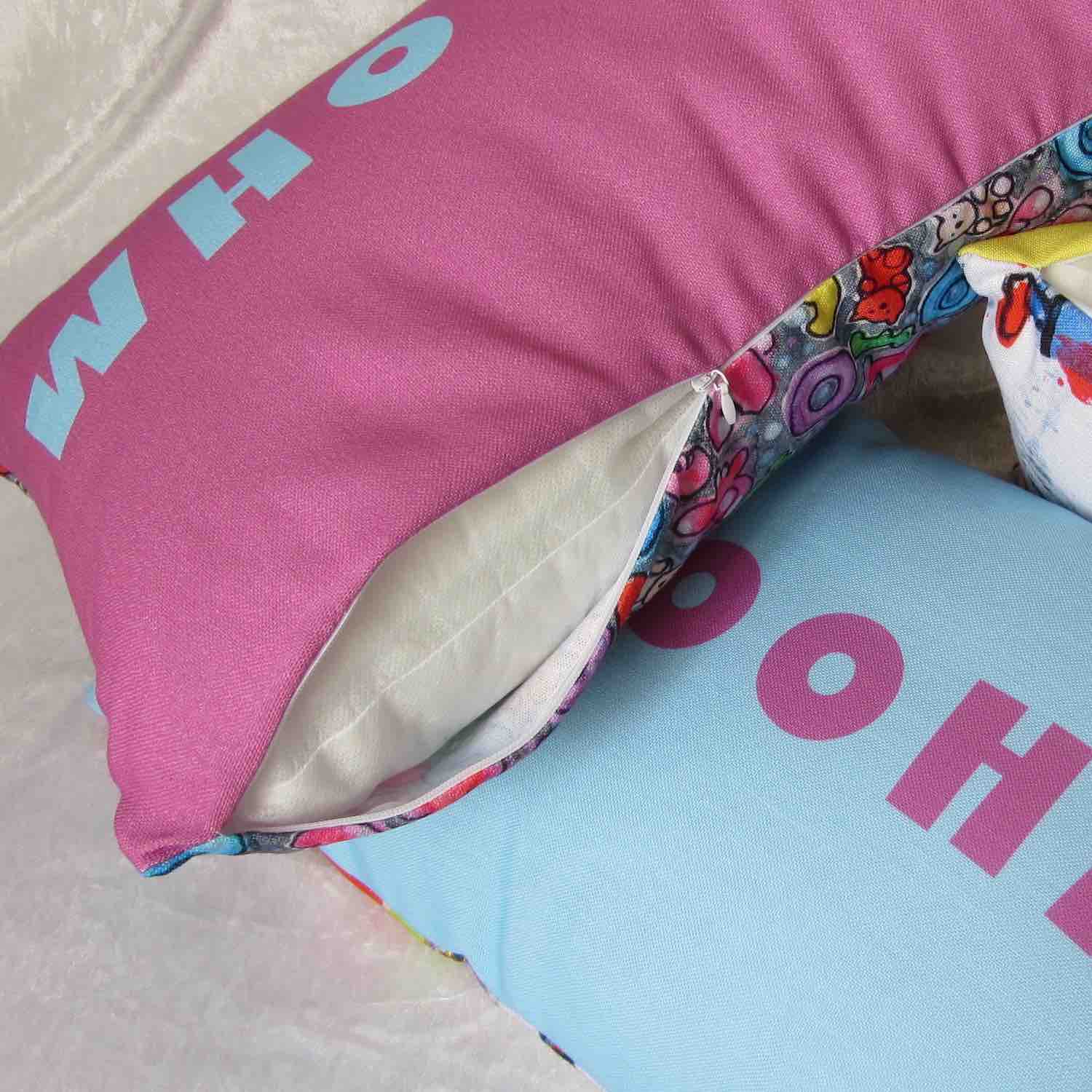 Detail view of playful style accent pillow with multicolor graphic whoopee slogan and pink fabric, white zipper, and insert.